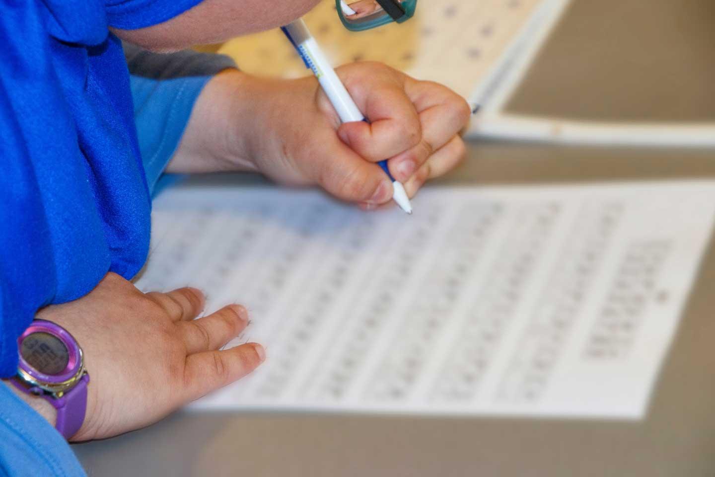 Individual filling out a form wearing a blue shirt and blue wrist watch