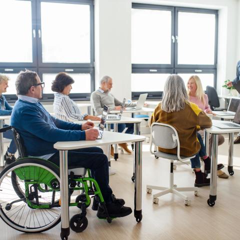 Man seating in a wheelchair in the middle of a classroom